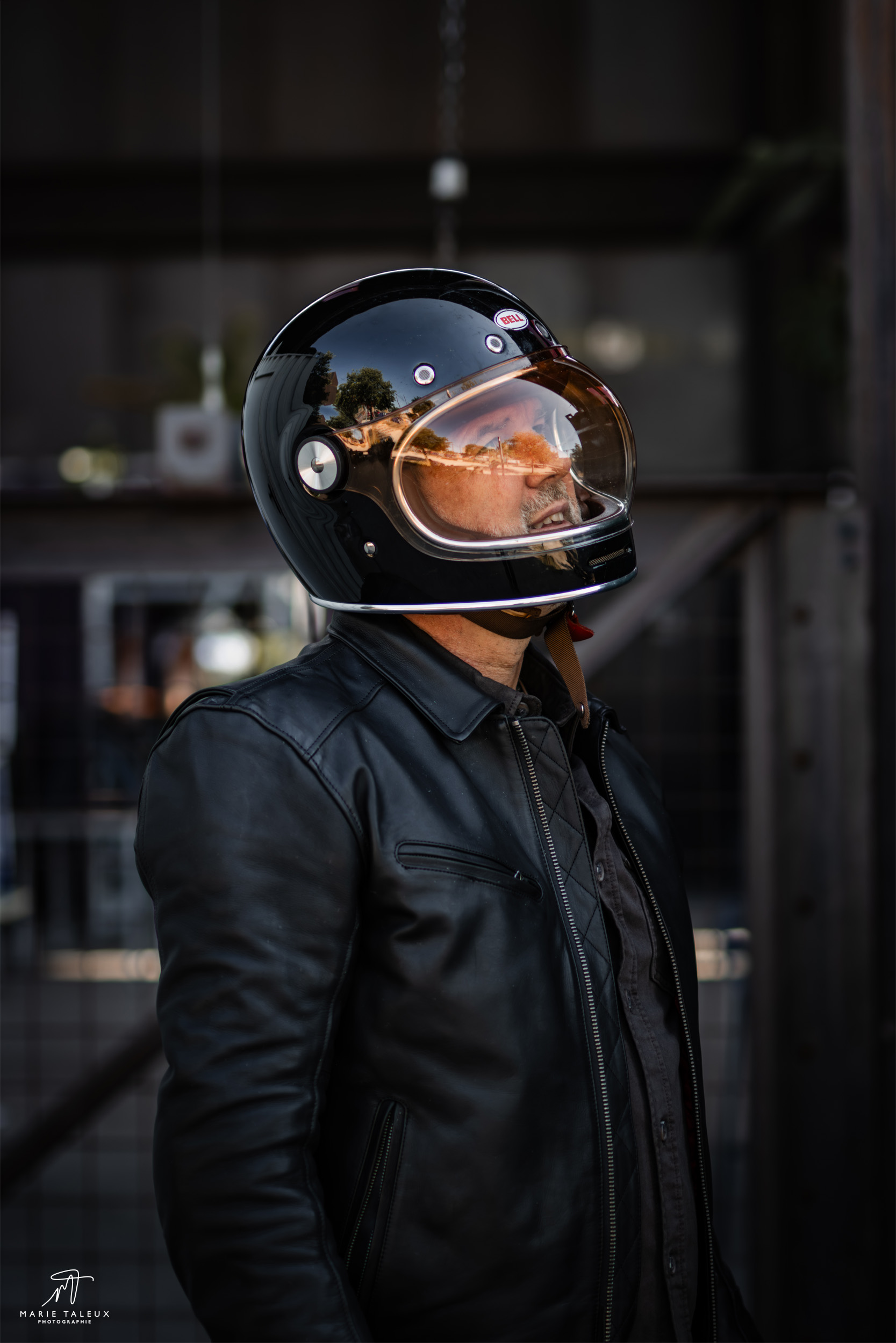seance-photo-portrait-homme-moto-lyon-1 Portrait d’un motard portant un casque noir et une veste en cuir, photographié de profil à Lyon.